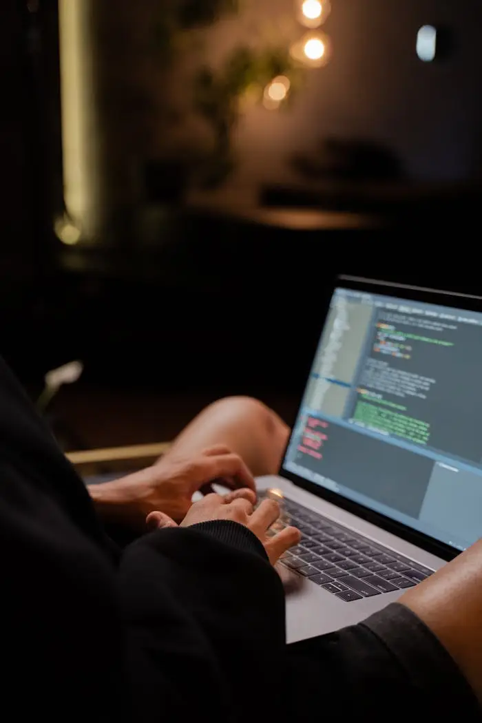 Mastering the First Impression: Your intriguing post title goes here Focused hands typing code on a laptop in a dimly lit room, showcasing programming activities.